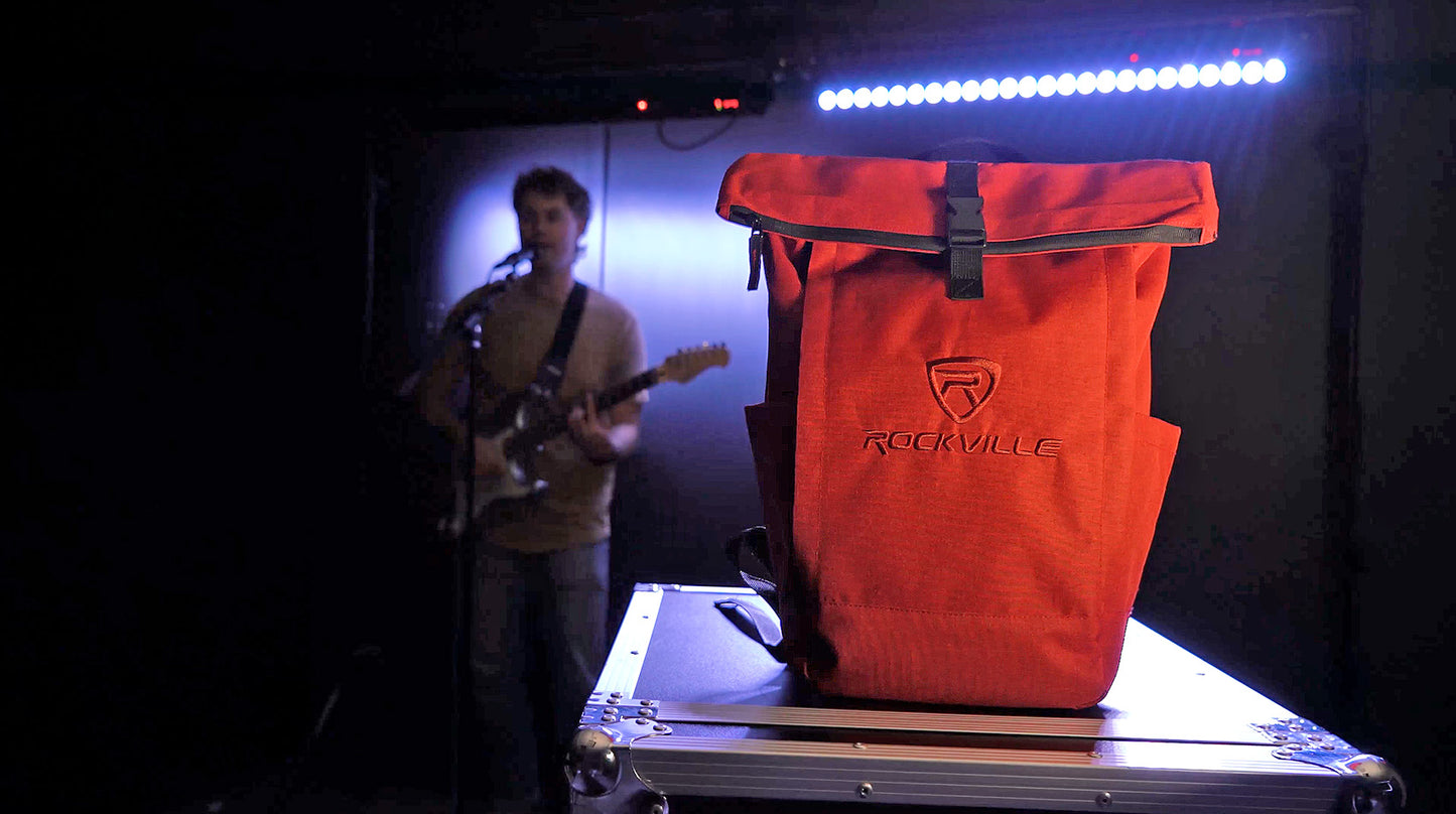 Person playing guitar next to a red bag with 'Rockville' branding on a dark stage.