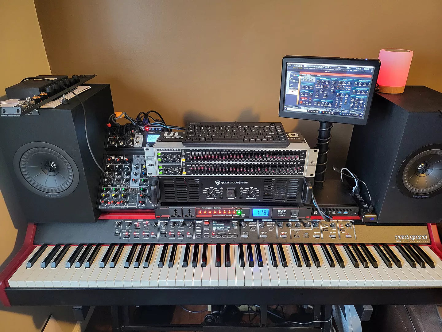Music production setup with keyboard, mixing console, and monitor on a desk.