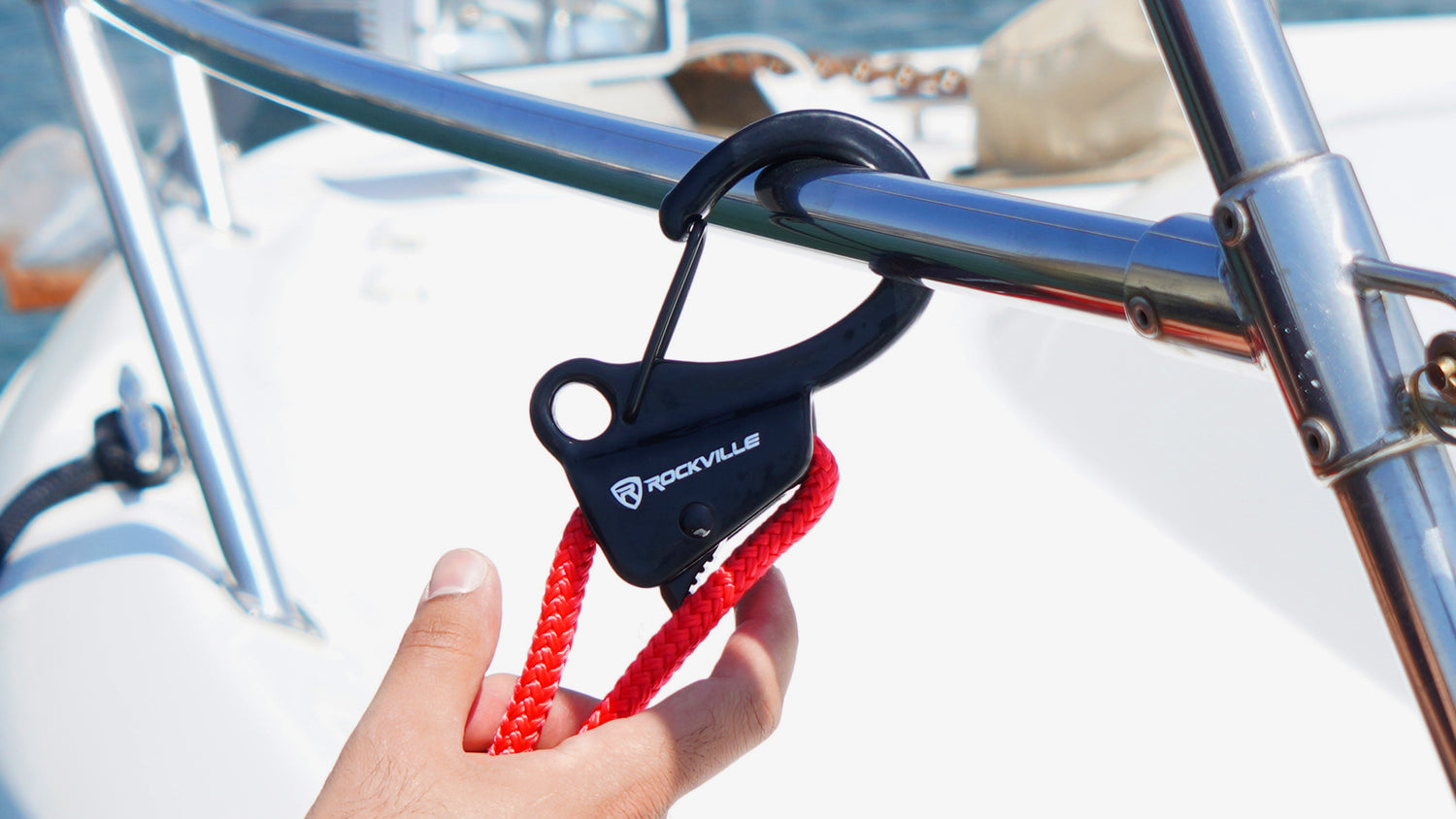Hand holding a black and red line on a boat railing with water and boat in the background